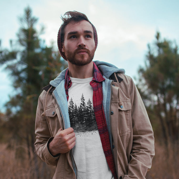 Man wearing a graphic t-shirt featuring illustrated forest tree line design, showcasing nature-inspired artwork.