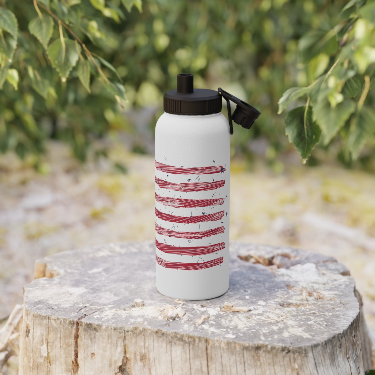 Lifestyle photo of a stainless steel water bottle with an illustrated American flag design, placed ion a log, highlighting its durability and eco-friendly style.